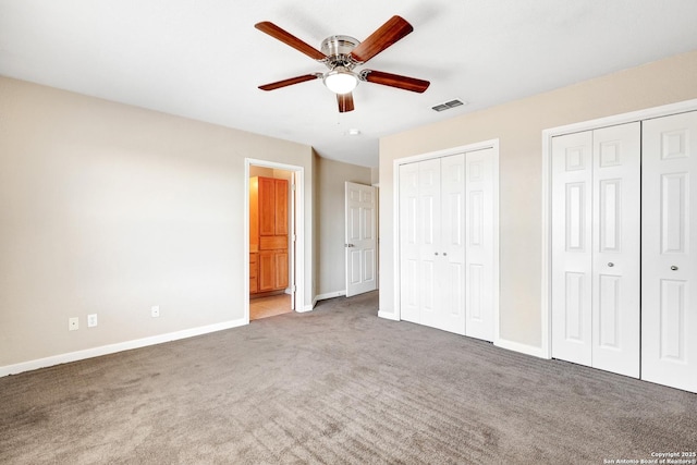 unfurnished bedroom with carpet floors, two closets, visible vents, ceiling fan, and baseboards