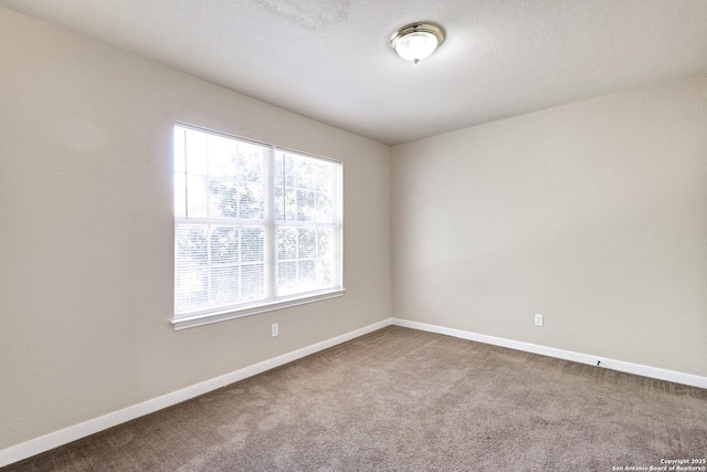 carpeted empty room with baseboards and a textured ceiling