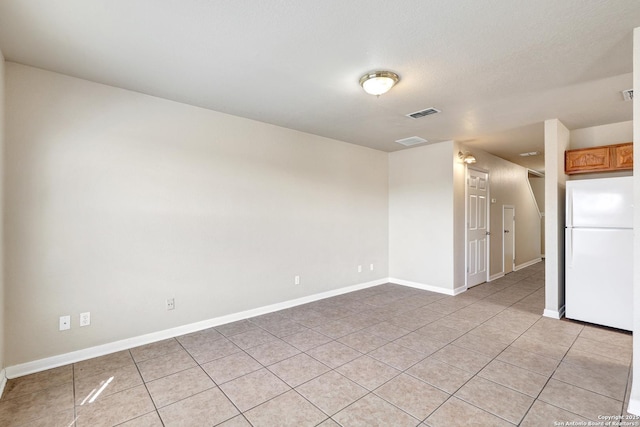 spare room with light tile patterned flooring, visible vents, and baseboards