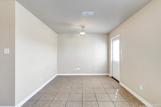 spare room featuring light tile patterned floors, baseboards, and visible vents