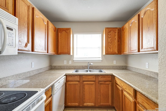 kitchen featuring brown cabinets, white appliances, light countertops, and a sink