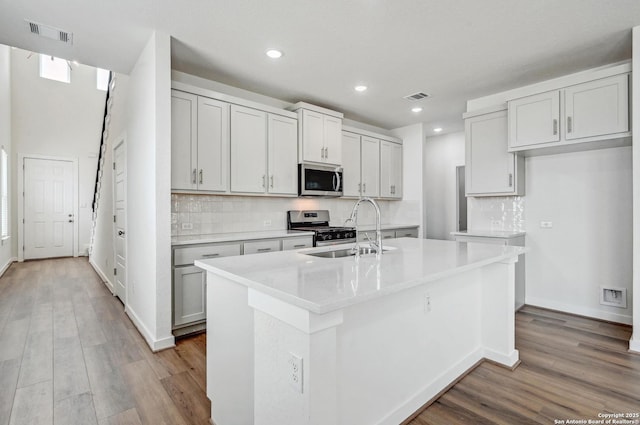 kitchen with appliances with stainless steel finishes, a sink, recessed lighting, wood finished floors, and visible vents