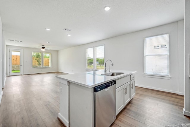 kitchen featuring a sink, light wood finished floors, dishwasher, light countertops, and visible vents
