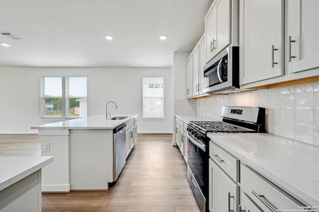 kitchen with stainless steel appliances, visible vents, a sink, and light wood finished floors