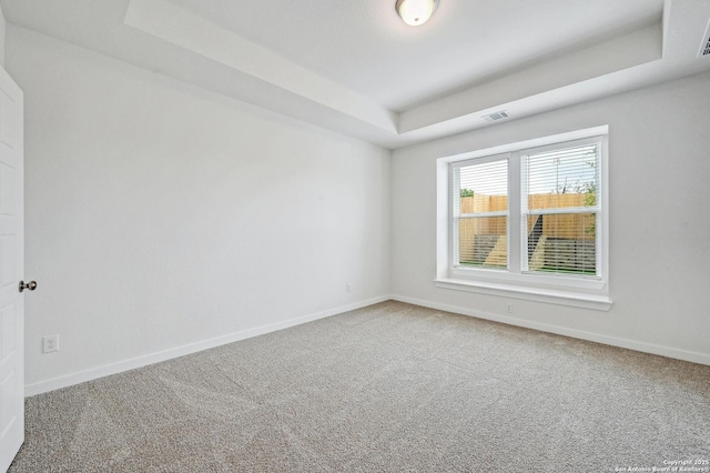 unfurnished room featuring a raised ceiling, baseboards, carpet, and visible vents