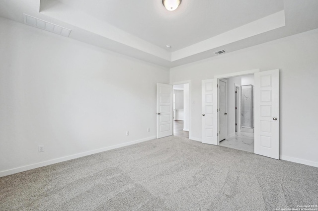 unfurnished bedroom with baseboards, visible vents, carpet, and a raised ceiling