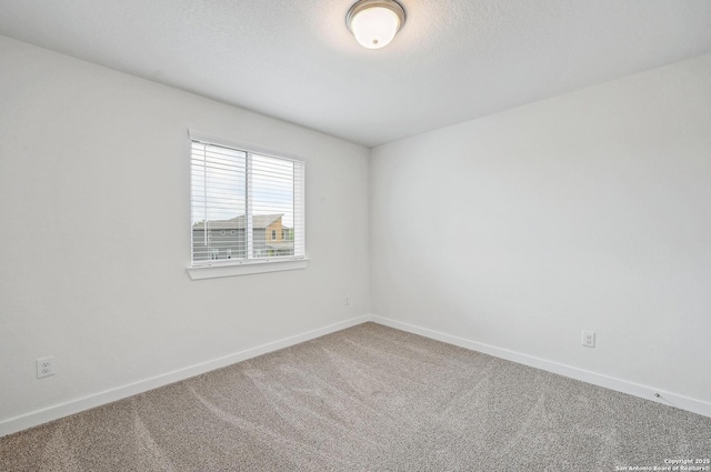carpeted empty room featuring baseboards