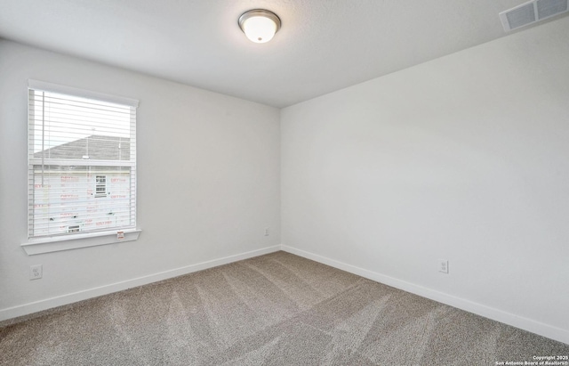 carpeted spare room featuring baseboards and visible vents