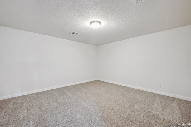 unfurnished room with carpet floors, a textured ceiling, visible vents, and baseboards