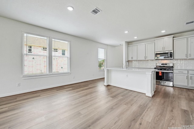 kitchen with visible vents, decorative backsplash, light wood-style floors, light countertops, and stainless steel appliances