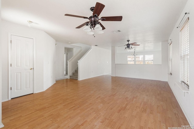 unfurnished living room with stairway, visible vents, ceiling fan, and light wood-style flooring