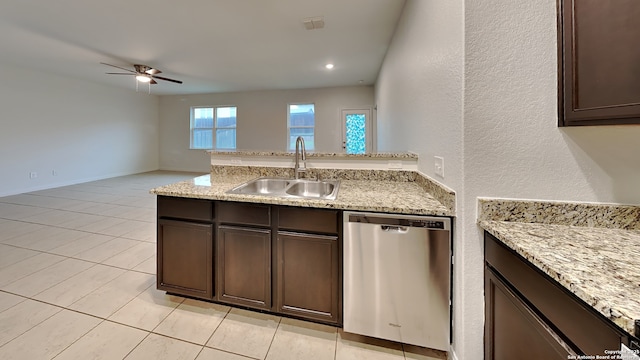 kitchen with light stone counters, stainless steel dishwasher, dark brown cabinetry, a sink, and a peninsula