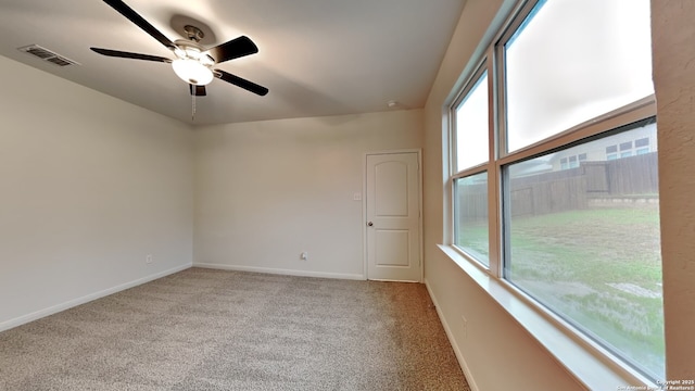 empty room featuring carpet floors, baseboards, visible vents, and a wealth of natural light