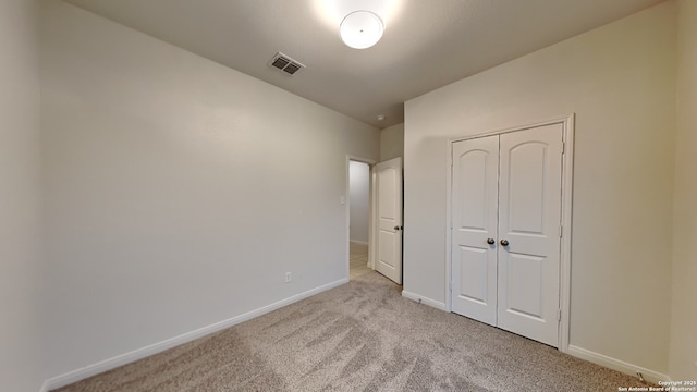 unfurnished bedroom with light carpet, baseboards, visible vents, and a closet