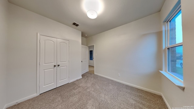 unfurnished bedroom featuring carpet floors, a closet, visible vents, and baseboards