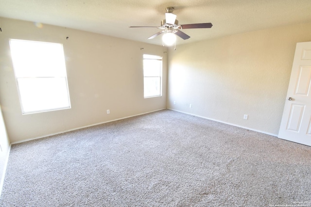 carpeted spare room featuring a ceiling fan and baseboards