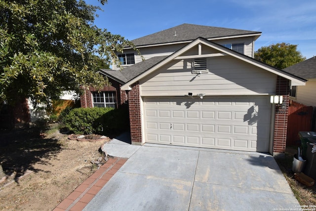 traditional home with a shingled roof, concrete driveway, brick siding, and an attached garage