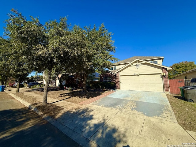 view of front of home with a garage, concrete driveway, brick siding, and fence