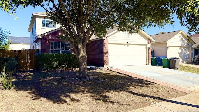 view of front of home with brick siding, driveway, an attached garage, and fence