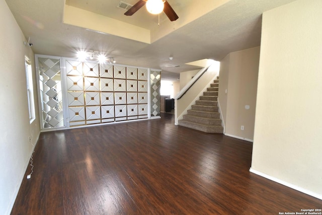 empty room featuring a raised ceiling, visible vents, wood finished floors, baseboards, and stairs