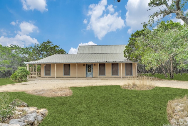 back of house with dirt driveway and metal roof