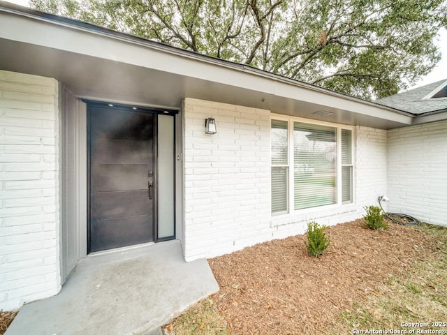 entrance to property featuring brick siding