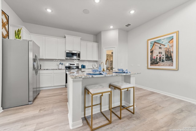 kitchen with appliances with stainless steel finishes, visible vents, white cabinetry, and tasteful backsplash