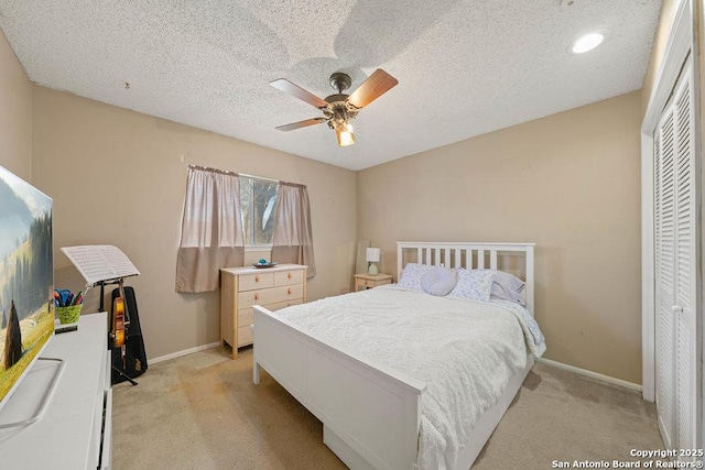 bedroom featuring a ceiling fan, baseboards, a textured ceiling, and light colored carpet