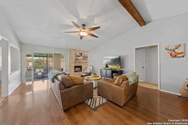 living area with lofted ceiling with beams, a brick fireplace, ceiling fan, and wood finished floors