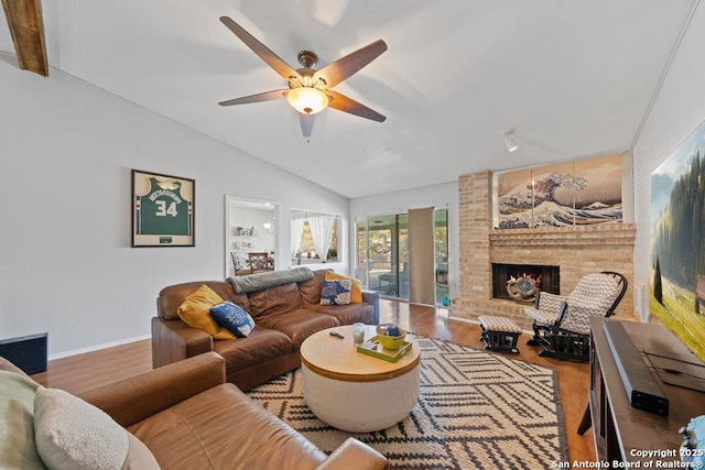 living room featuring lofted ceiling, a fireplace, a ceiling fan, and wood finished floors