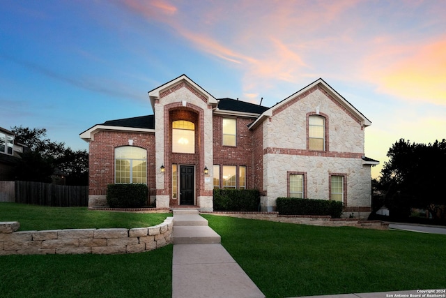 traditional-style house featuring a front yard, stone siding, and brick siding