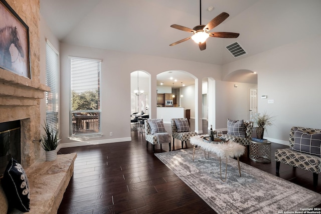 living area featuring dark wood finished floors, vaulted ceiling, arched walkways, and baseboards