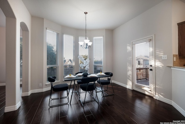 dining space with arched walkways, dark wood-type flooring, a chandelier, and baseboards