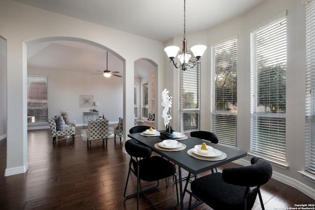 dining space featuring dark wood-type flooring, arched walkways, baseboards, and ceiling fan with notable chandelier