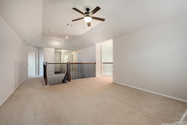 unfurnished room with carpet floors, a ceiling fan, visible vents, vaulted ceiling, and baseboards