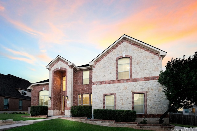 view of front of house featuring stone siding, brick siding, and a front lawn