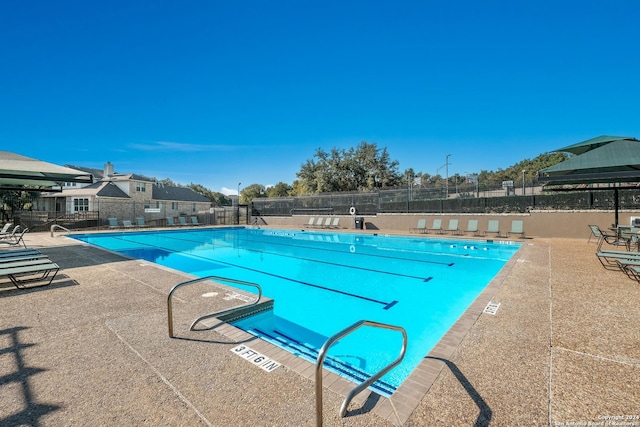 community pool with a patio area and fence