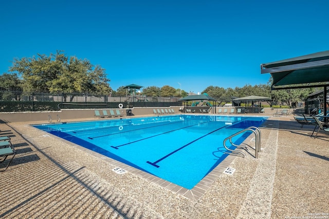 pool with a patio area, fence, and a gazebo