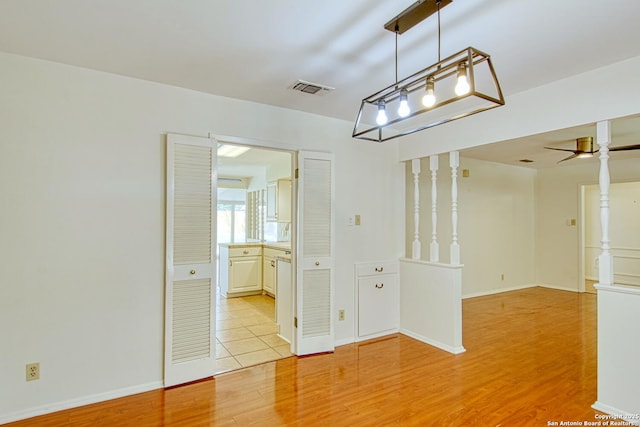 empty room featuring light wood-style flooring, visible vents, and baseboards