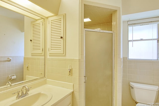 full bathroom with a wainscoted wall, tile walls, toilet, a stall shower, and vanity