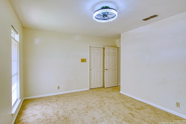 carpeted empty room with visible vents and baseboards