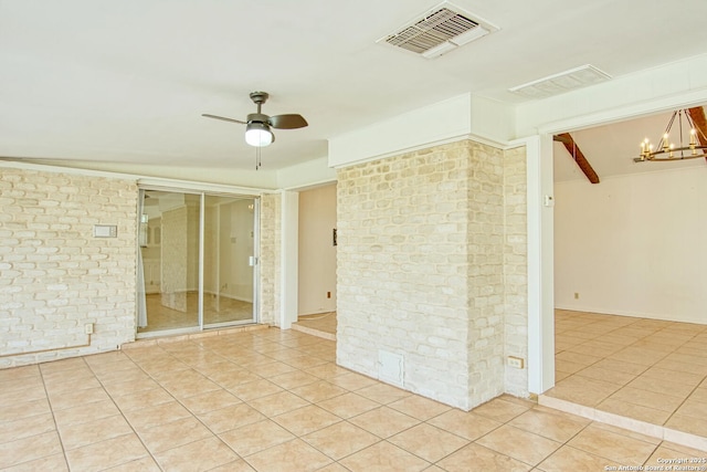 unfurnished room with ceiling fan with notable chandelier, brick wall, light tile patterned flooring, and visible vents