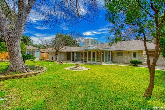 back of property with brick siding, a lawn, a chimney, and a sunroom