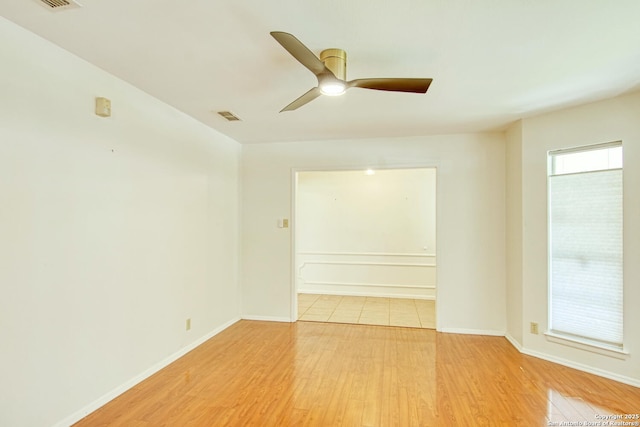 empty room with a ceiling fan, baseboards, visible vents, and wood finished floors