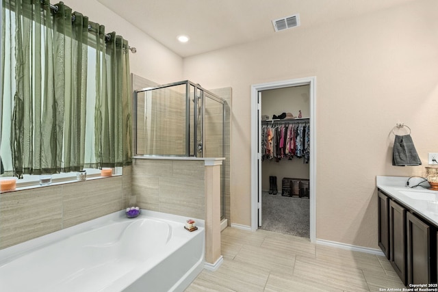 bathroom with a shower stall, a spacious closet, visible vents, and a bath