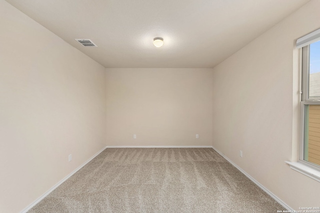 carpeted spare room featuring baseboards and visible vents