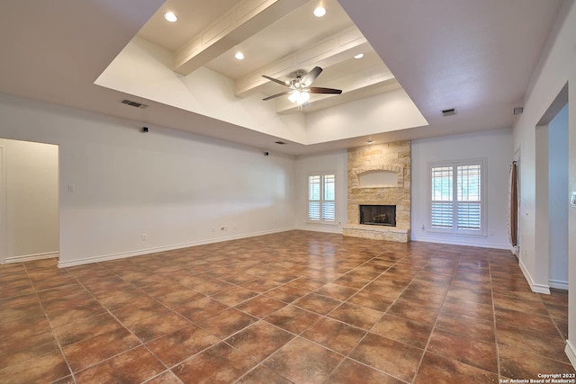 unfurnished living room featuring visible vents, baseboards, ceiling fan, a fireplace, and beam ceiling