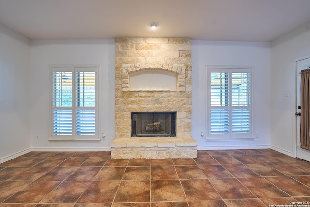 unfurnished living room with a fireplace, tile patterned floors, and baseboards