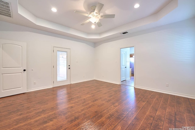 unfurnished room featuring wood-type flooring, a raised ceiling, visible vents, and baseboards