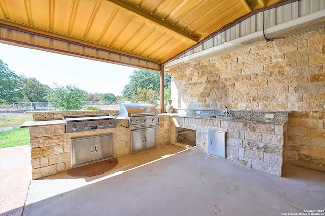 view of patio featuring fence, an outdoor kitchen, a sink, and area for grilling